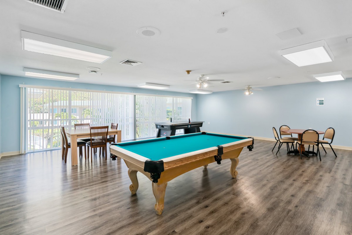A spacious game room featuring a pool table and foosball table with seating areas.
