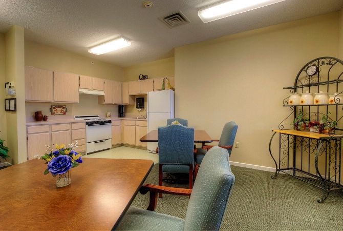 A cozy kitchen and dining area with tables, chairs, a refrigerator, and a stove.