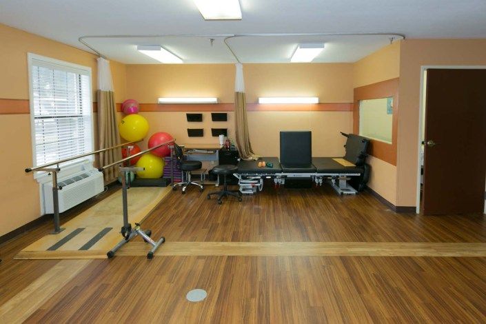 A physical therapy room equipped with exercise balls, treatment tables, and other rehabilitation equipment.
