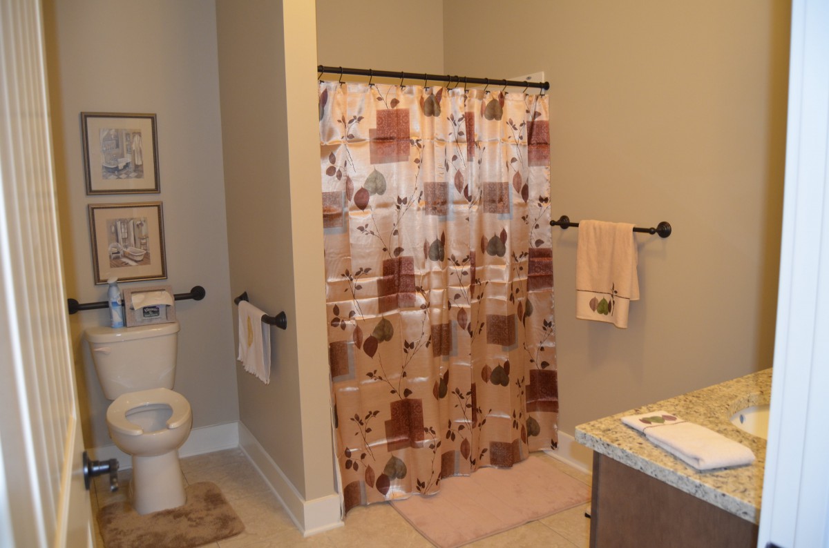 A cozy bathroom featuring a floral shower curtain, a toilet, and neatly hung towels.