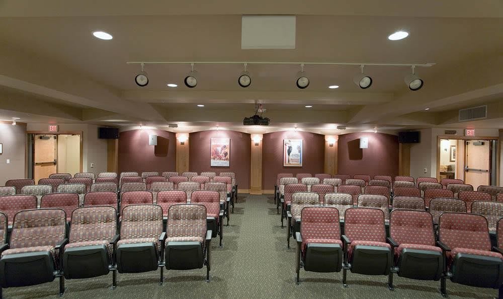 An empty theater auditorium with rows of red and black seats.