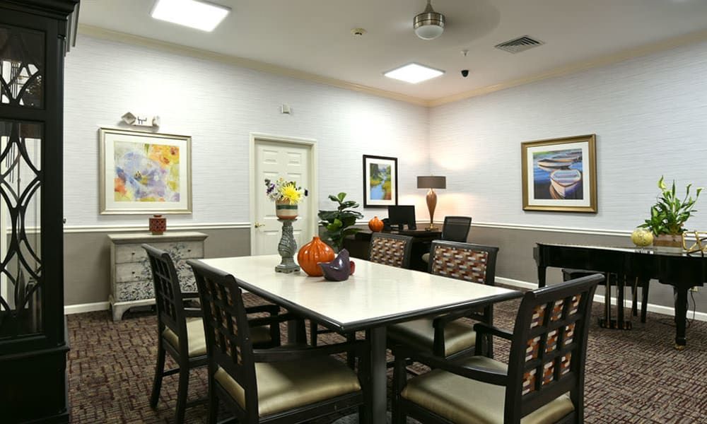 A well-decorated dining room with a large table surrounded by chairs, adorned with colorful paintings and decorative items.