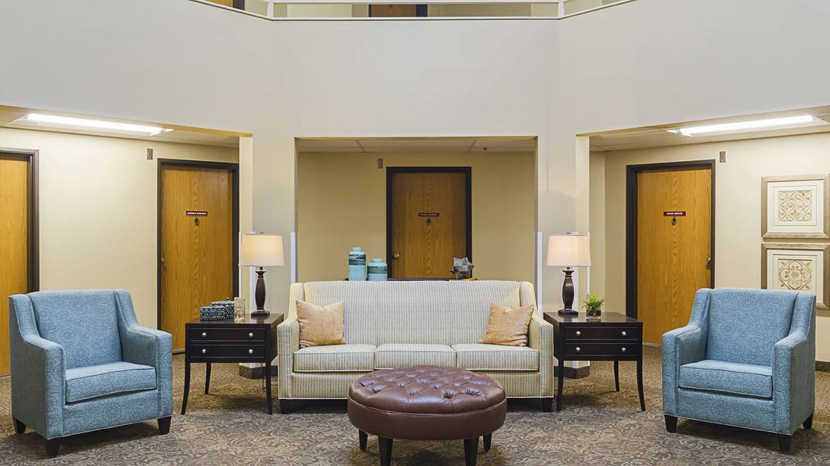 A cozy hotel lobby featuring a comfortable sofa, two side tables with lamps, and a round coffee table.
