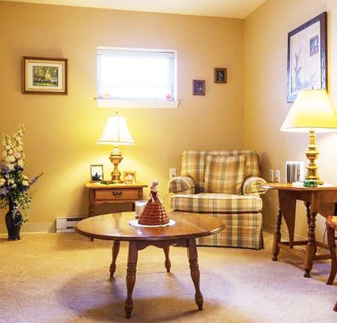 A cozy living room with a plaid armchair, two lamps, and a wooden coffee table.