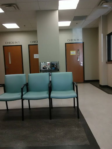 A waiting area in a medical facility with teal chairs and closed doors.