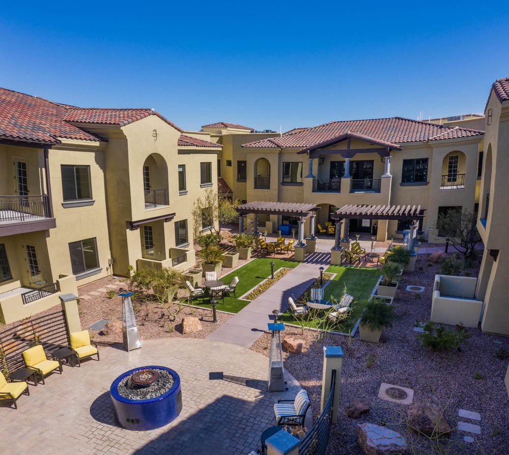 A well-maintained apartment complex with a landscaped courtyard featuring outdoor seating and a fire pit.
