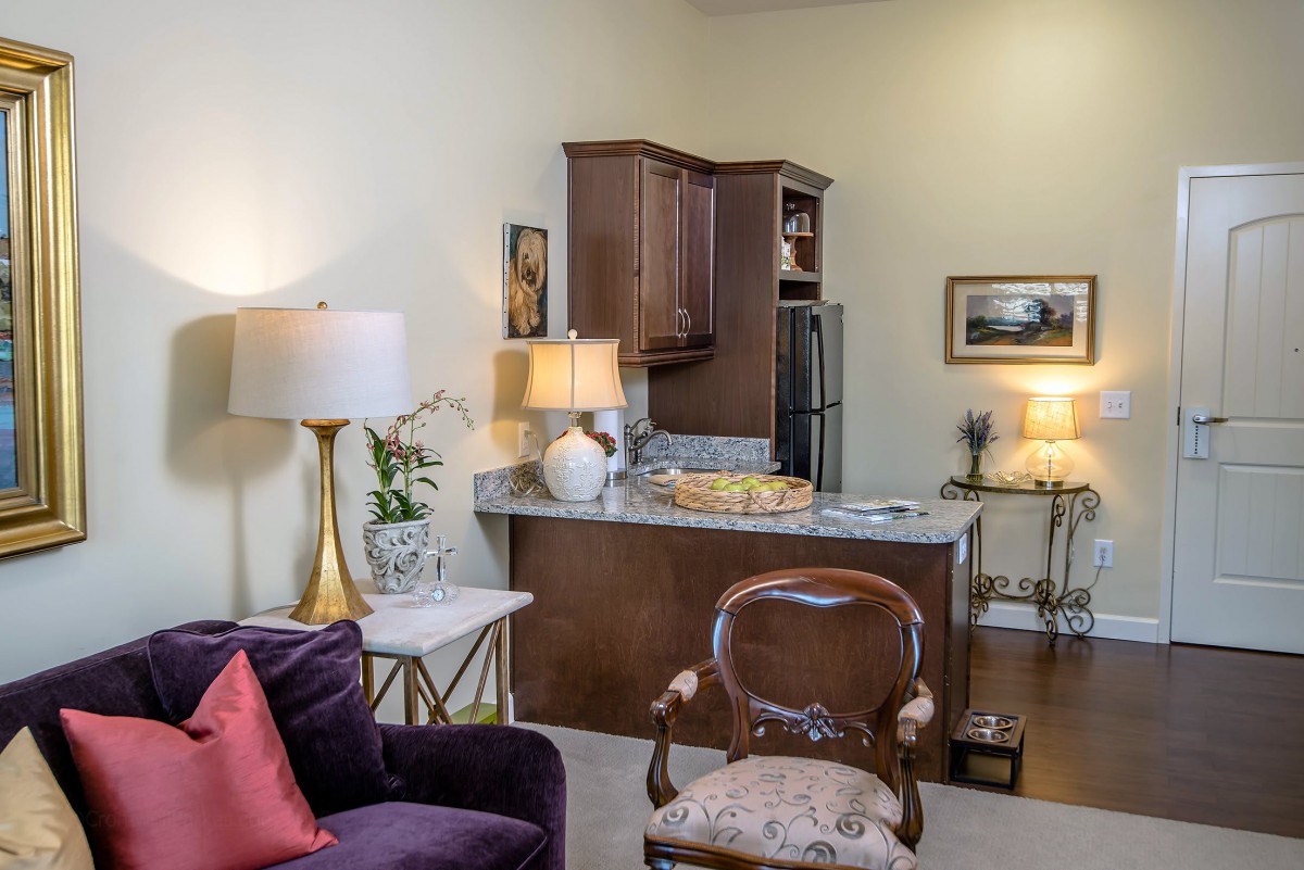 A cozy living room space with a view of the kitchen, featuring elegant furniture and warm lighting.