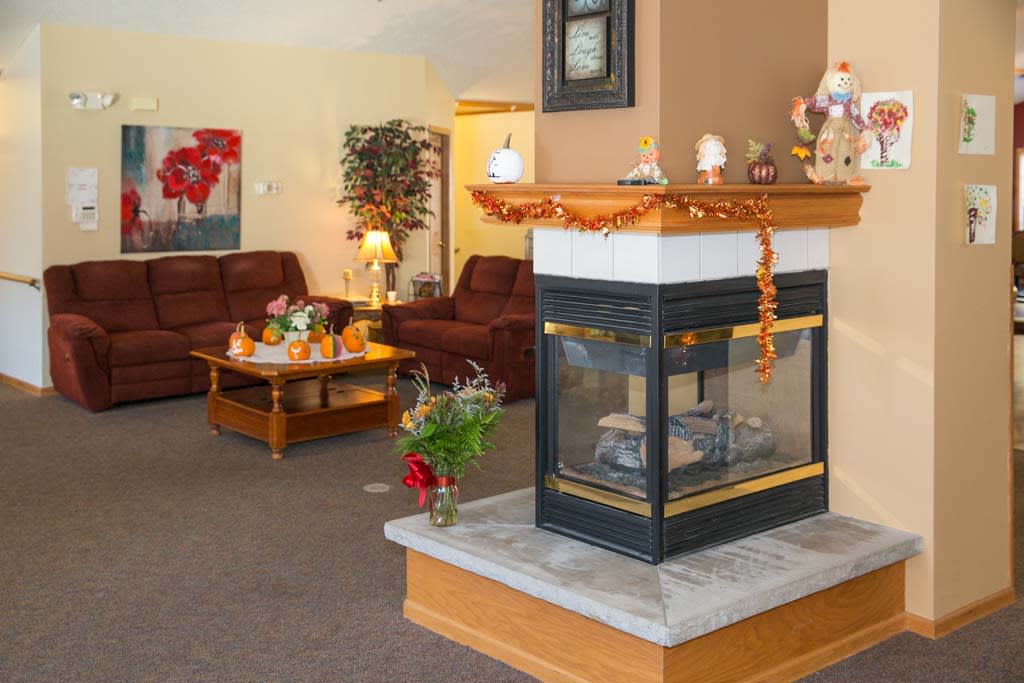 A cozy living room with a central fireplace and autumn-themed decor.