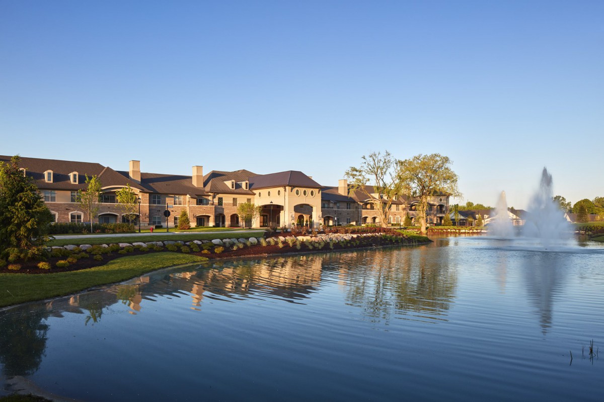 A luxurious waterfront mansion with a grand architectural design, beautifully reflected in the calm waters.