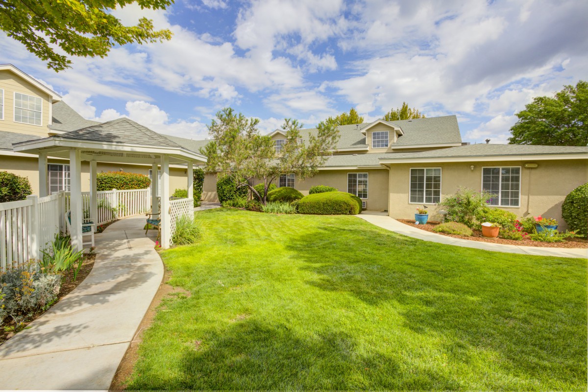 A suburban house with a well-maintained lawn and a gazebo in the garden.