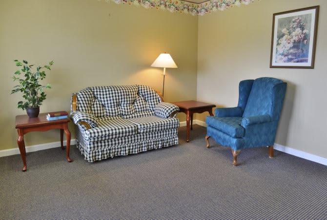 A cozy living room with a checkered sofa, a blue armchair, and warm lighting.