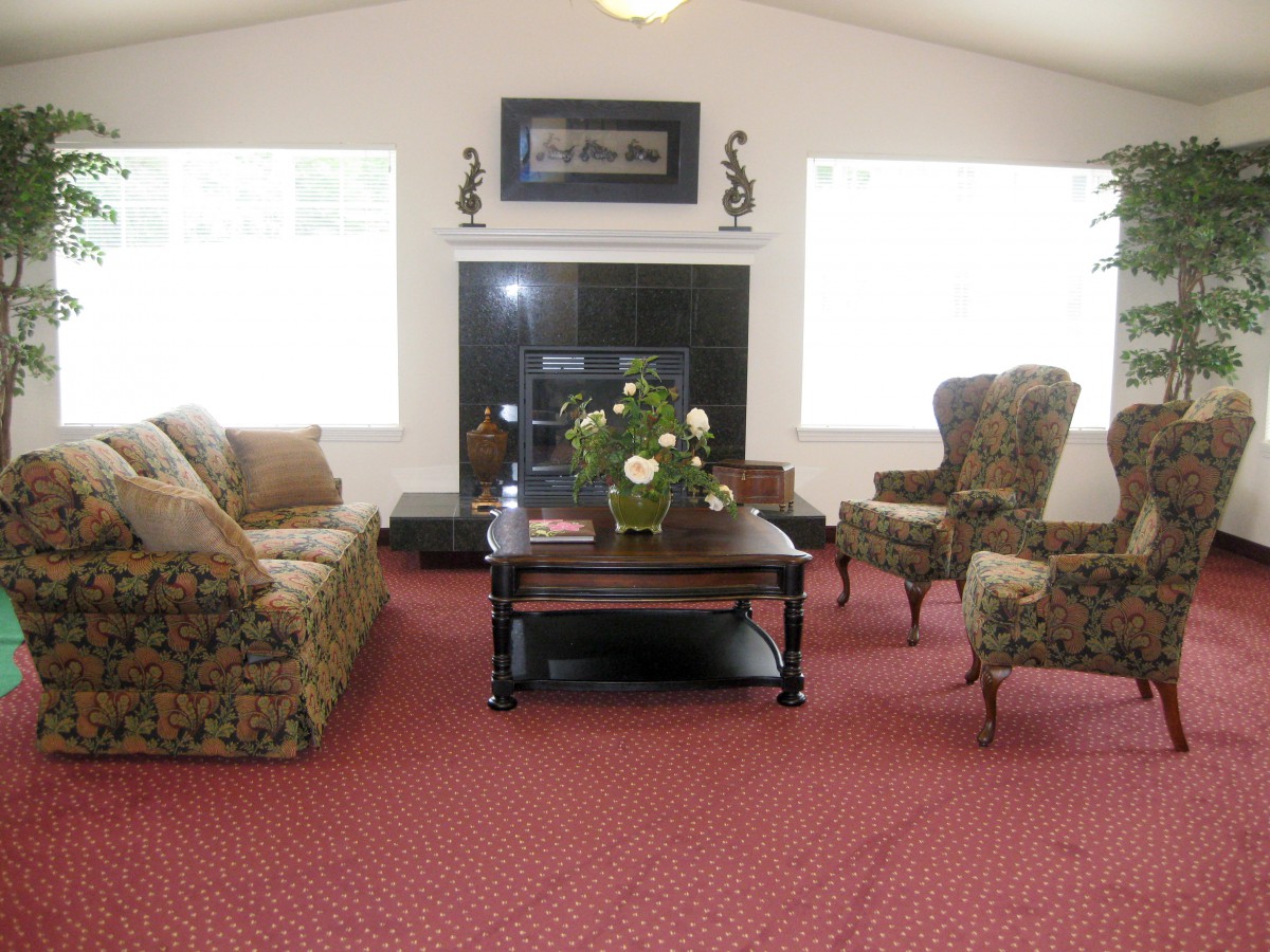 A cozy living room with patterned furniture and a central coffee table on a red carpet.