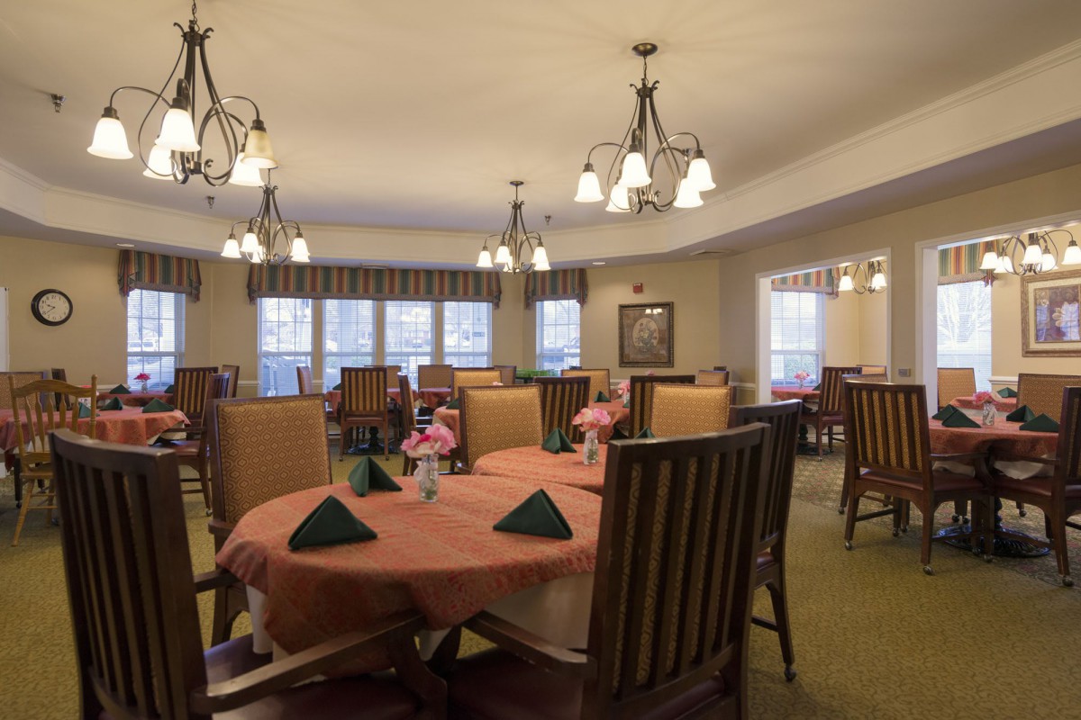 A cozy dining room with neatly arranged tables and elegant chandeliers.