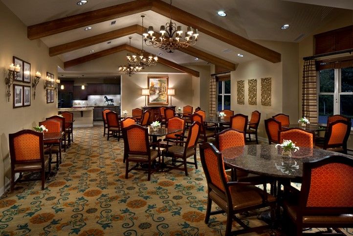 A cozy dining area with elegant chandeliers and neatly arranged tables and chairs.