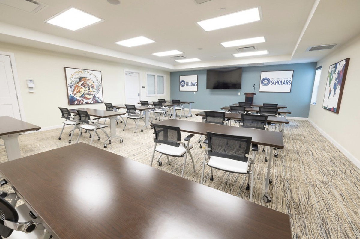 A modern conference room equipped with tables, chairs, and a presentation screen.