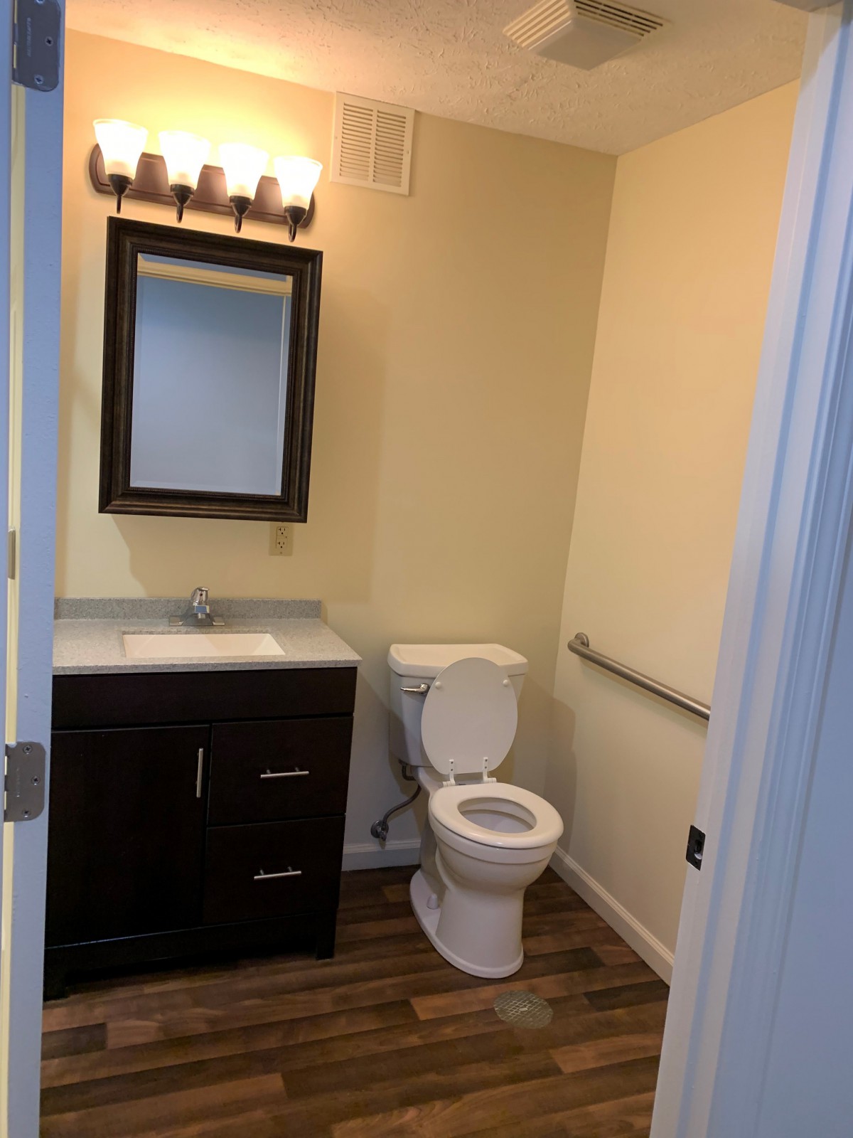 A small bathroom with a toilet, sink, and mirror under warm lighting.