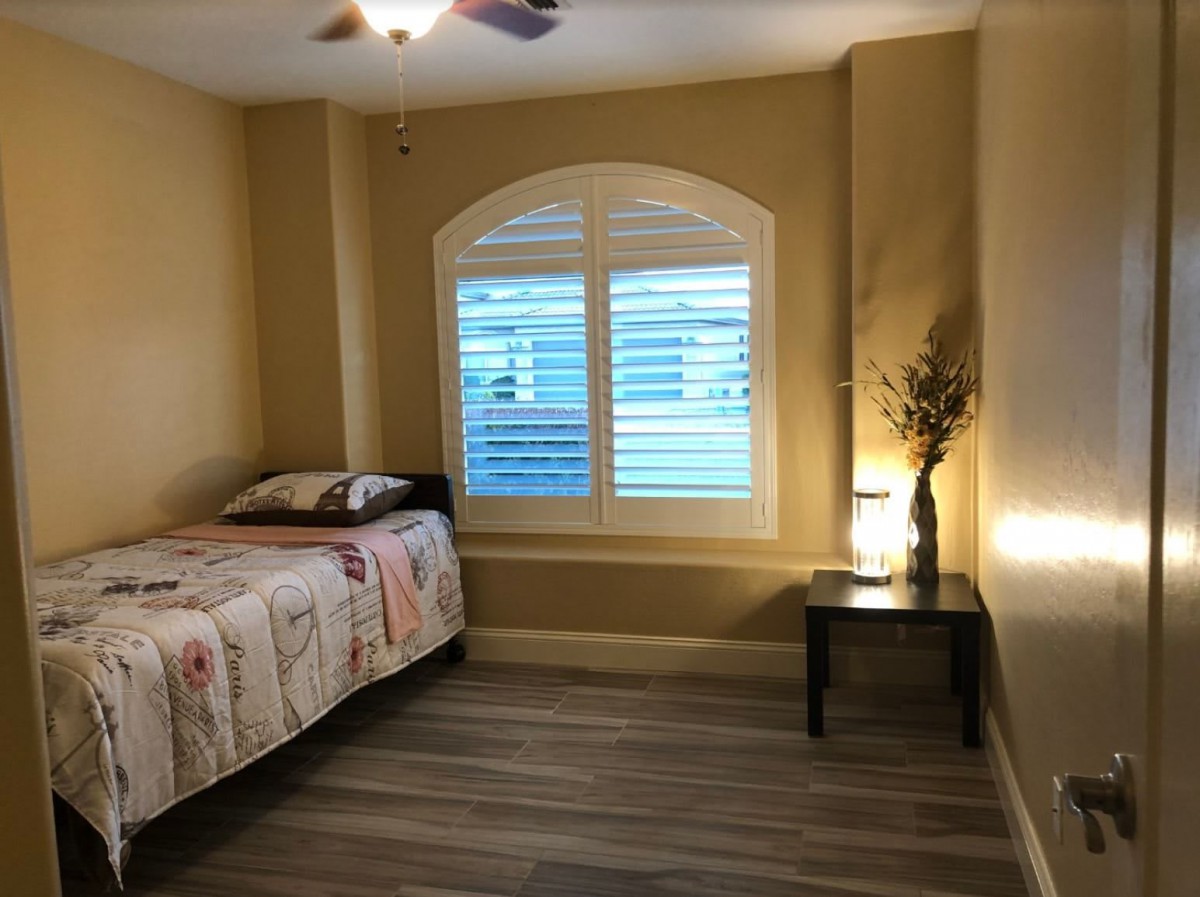 A cozy bedroom with a single bed and a nightstand beside a window.