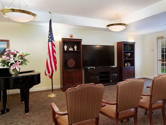 A cozy living room with a piano, television, and an American flag.