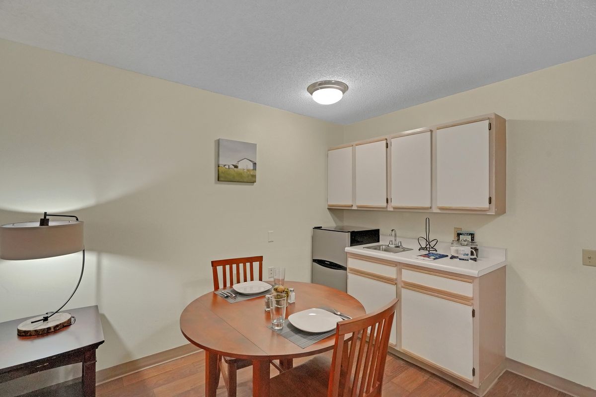 A small kitchen with a dining table and chairs, featuring cabinets, a sink, and appliances.