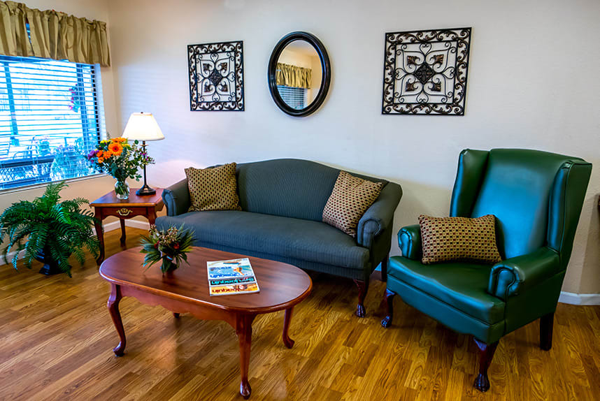 A cozy living room with a sofa, armchair, and coffee table complemented by decorative wall art and a mirror.