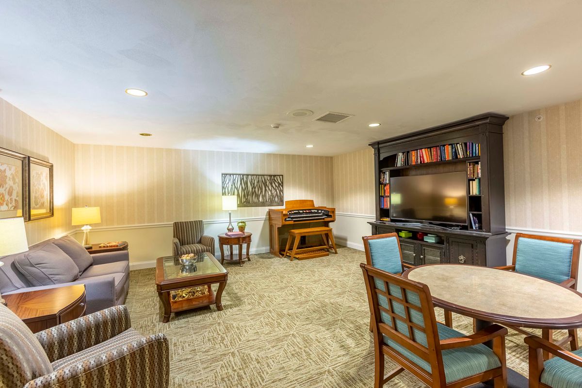 A cozy living room featuring a piano, television, and comfortable seating area.