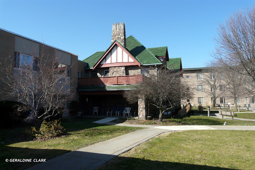A picturesque view of a building featuring traditional architectural elements, surrounded by green grass and clear blue skies.