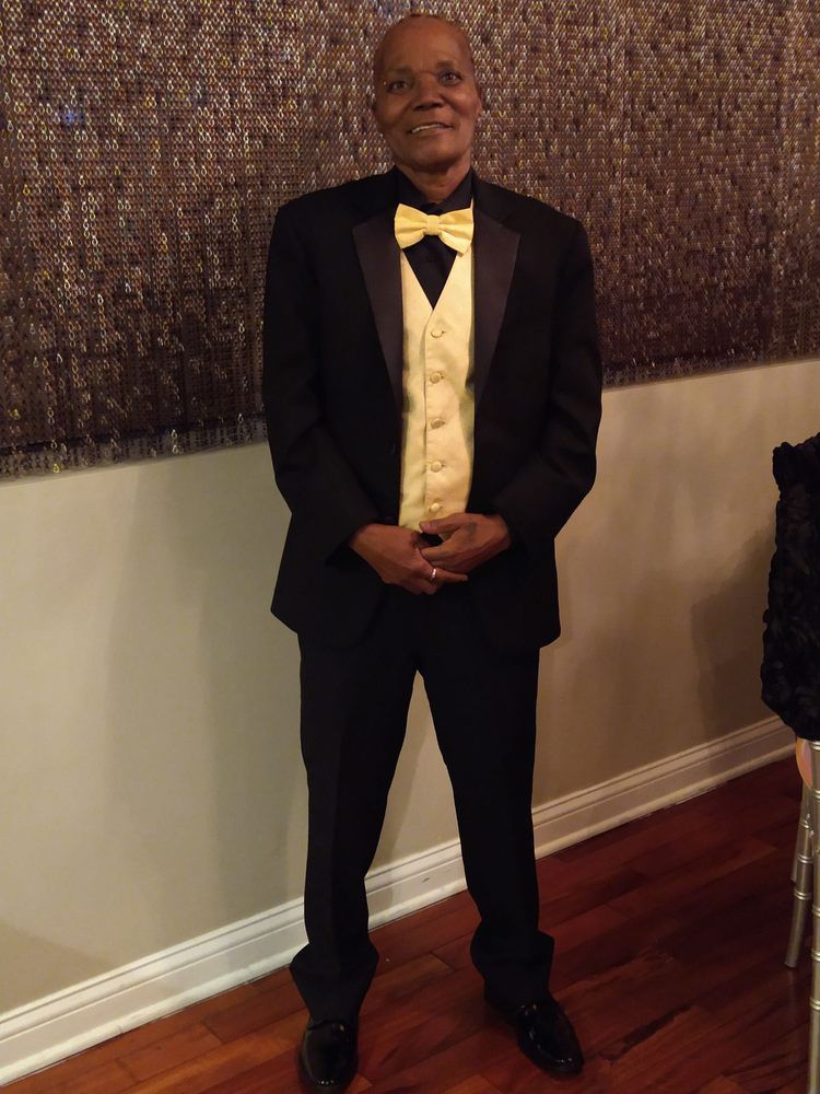 A person in formal attire, wearing a black suit with a yellow vest and bow tie.
