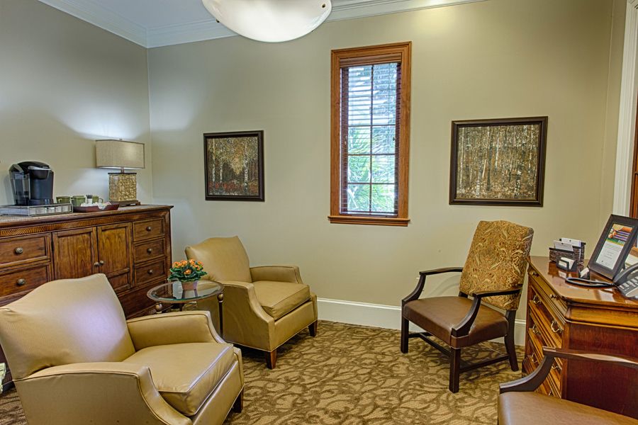 A cozy waiting room with upholstered chairs, artwork on the walls, and a window providing natural light.