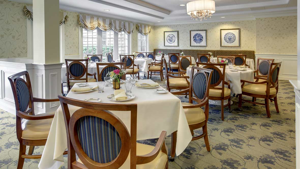 An elegant dining room with neatly arranged tables and chairs, set for guests.