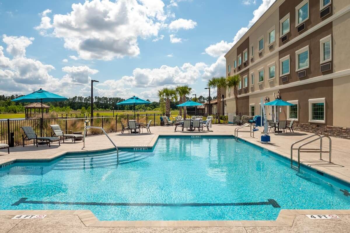 A sunny outdoor hotel pool area with chairs and umbrellas for relaxation.