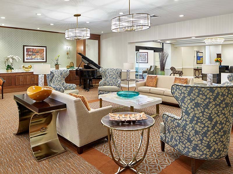 A modern living room with elegant furniture and decor, featuring a grand piano and stylish lighting.