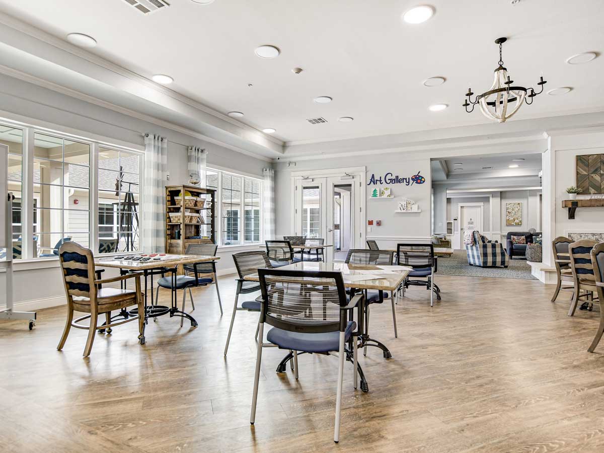 A modern lounge area with tables and chairs, featuring bright lighting and wooden flooring.