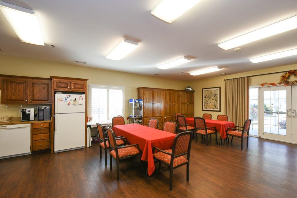 A dining room with a large table, chairs, and a refrigerator.