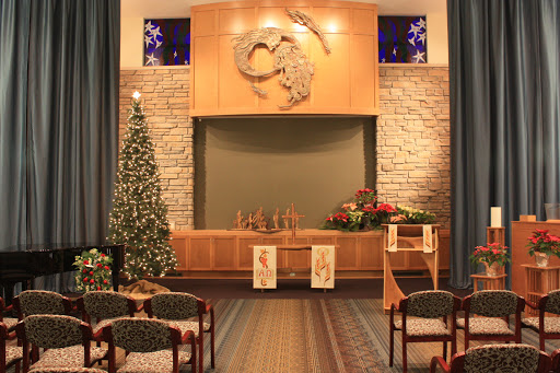 A serene interior of a church adorned with festive Christmas decorations, featuring a beautifully decorated tree and an altar.