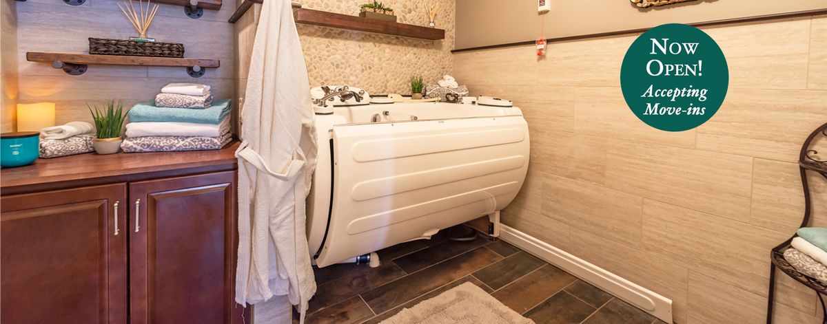 A modern bathroom featuring a jacuzzi-style bathtub with wood accents and tile flooring.