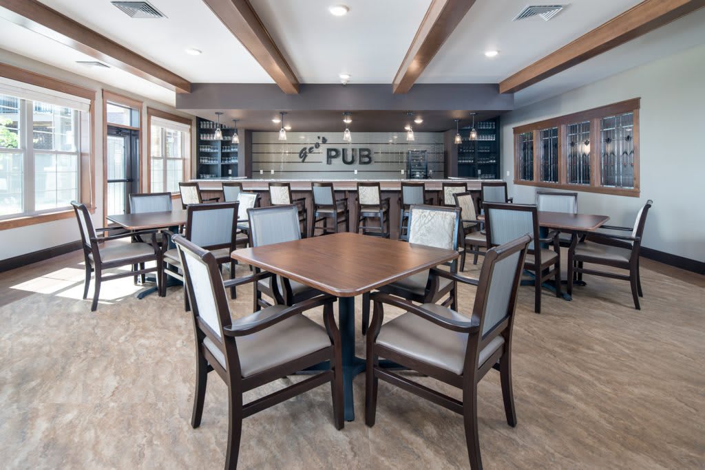 A modern pub interior with neatly arranged tables and chairs, featuring a stylish bar area.