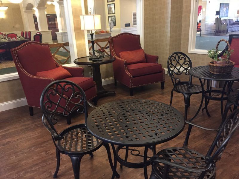A cozy lounge area featuring red armchairs and metal tables with matching chairs.