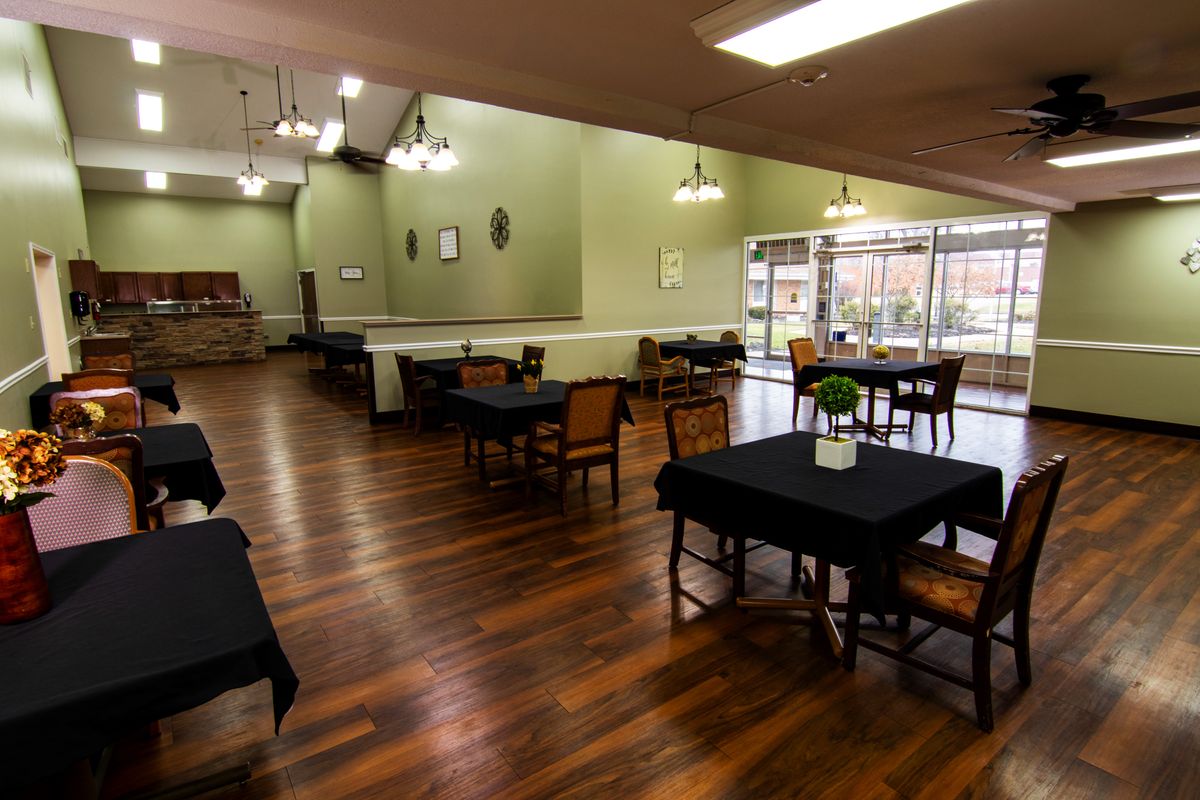 A spacious dining area with wooden floors and neatly arranged tables and chairs.