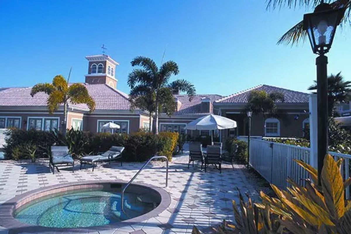 A sunny outdoor area featuring a hot tub surrounded by a patio with palm trees at a resort.