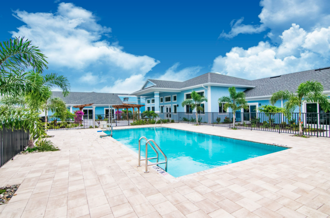 A luxurious resort with a clear blue swimming pool under a bright sky.
