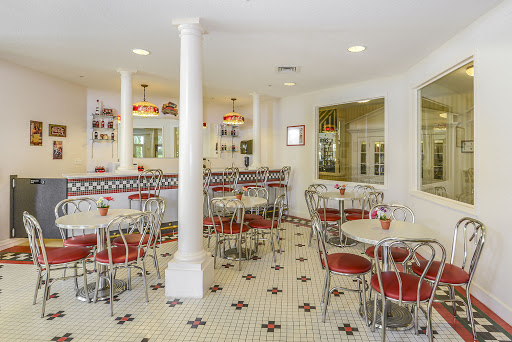 A cozy diner interior featuring red and silver furniture, a classic checkered floor, and warm lighting.