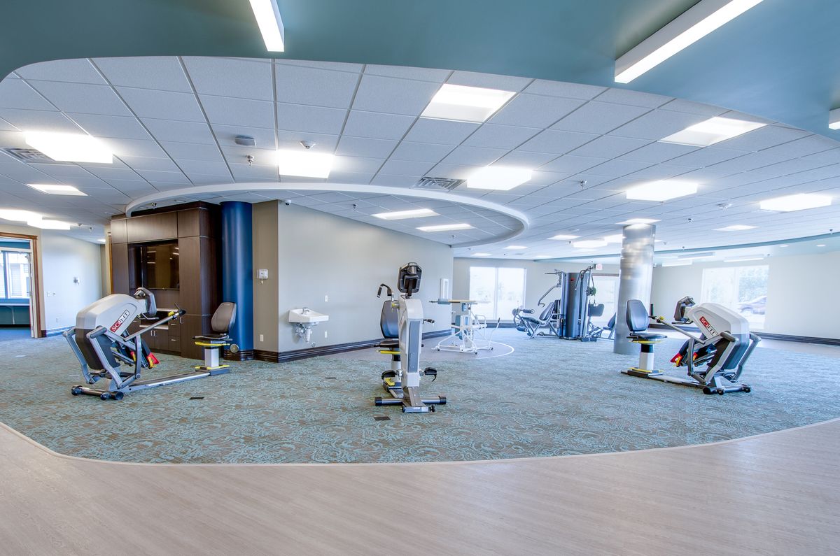 A modern and spacious gym with various exercise equipment arranged in a bright, open workout area.