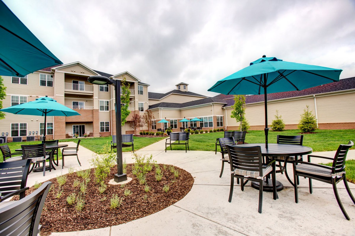 A scenic outdoor patio area with tables and umbrellas in front of a residential building.