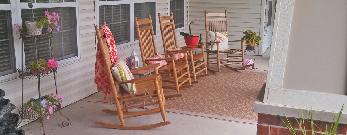 A cozy porch with wooden rocking chairs and colorful cushions.