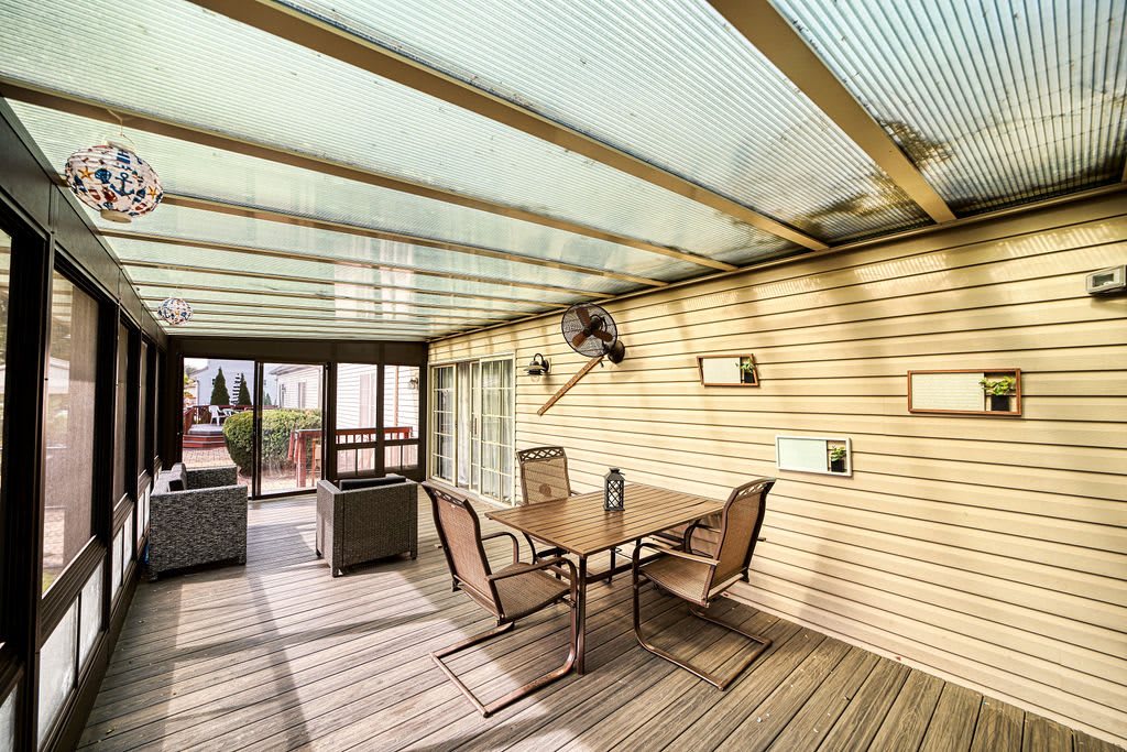 A cozy outdoor patio with a glass roof, featuring a table and chairs for relaxation.