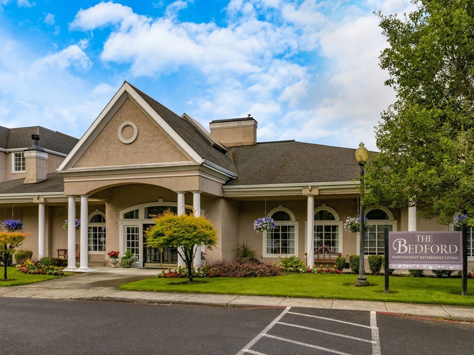 A charming building with a gabled roof and columns, set against a partly cloudy sky.