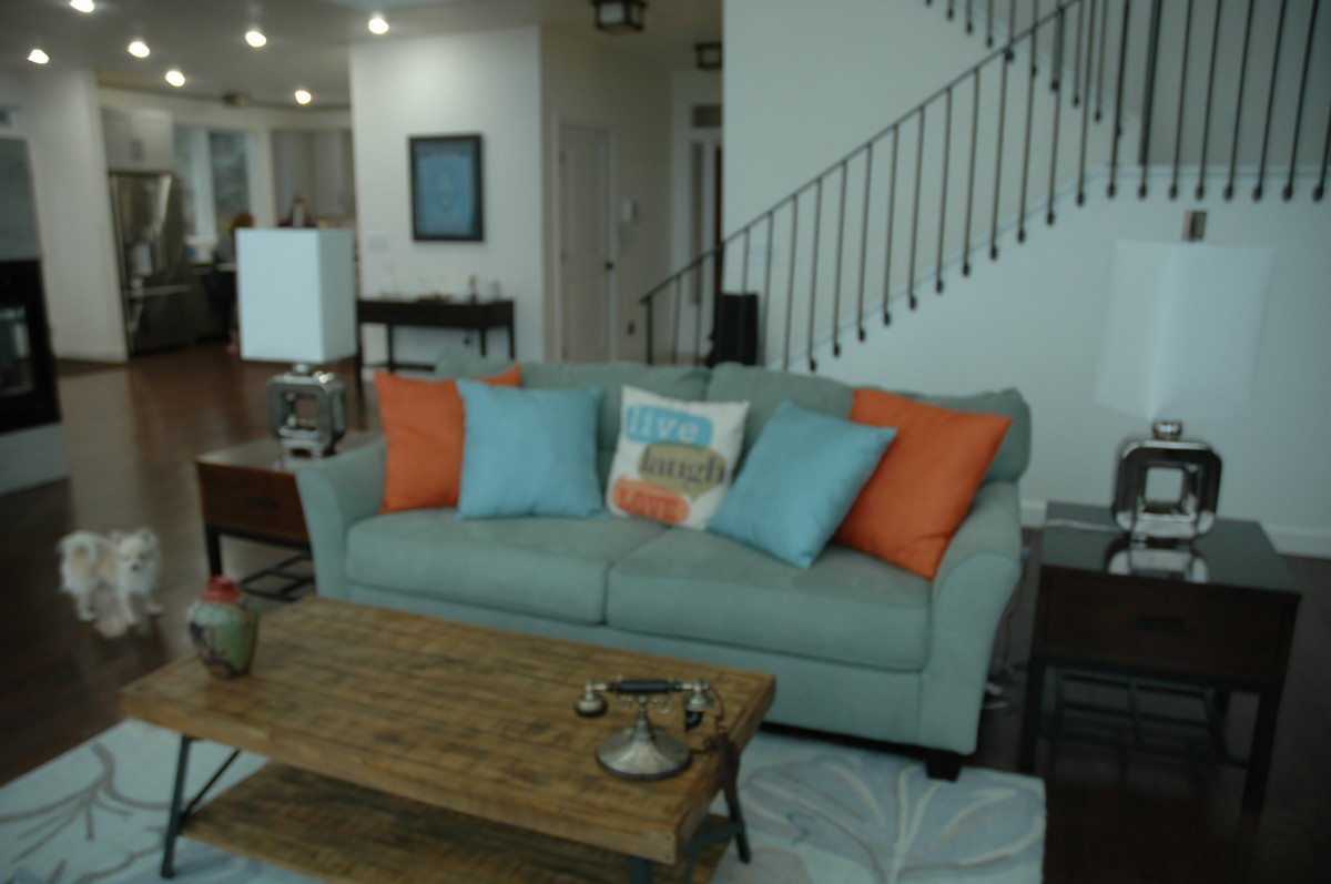 A modern living room featuring a light gray sofa adorned with colorful pillows and a rustic wooden coffee table.