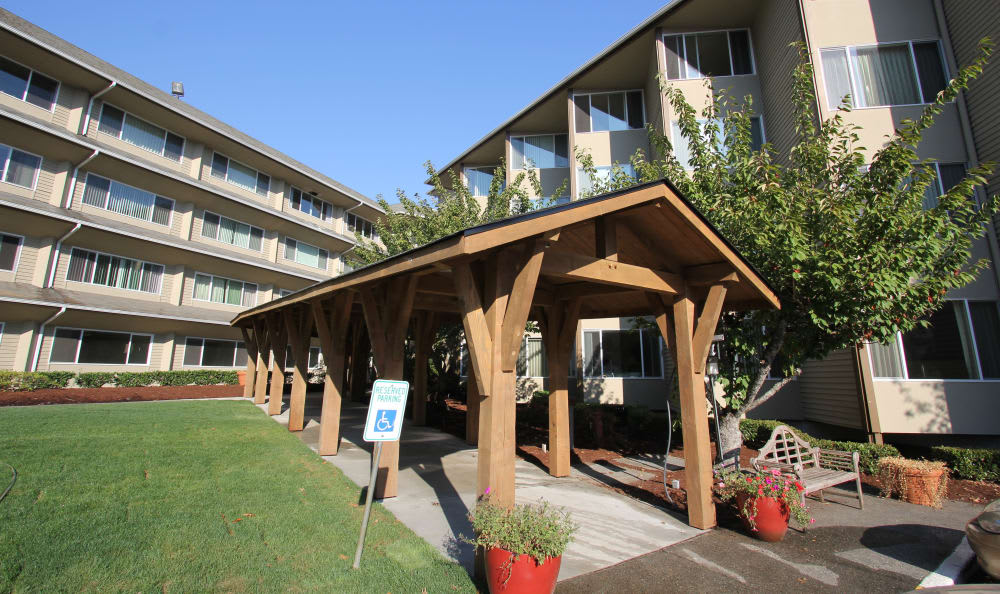 A view of a building entrance with a wooden walkway leading to an apartment complex under a clear blue sky.