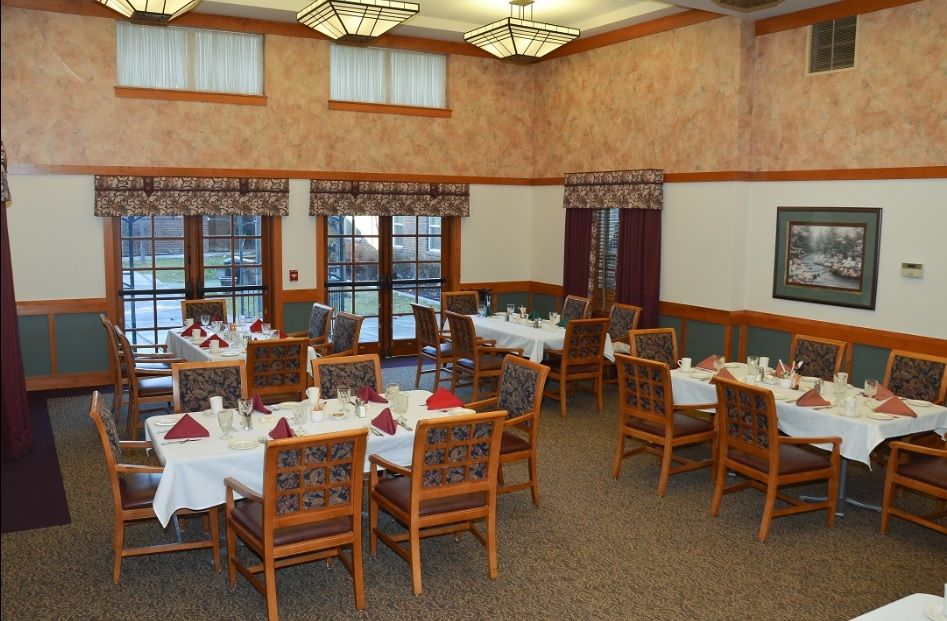 An elegantly set dining room with multiple tables and chairs, ready for guests.