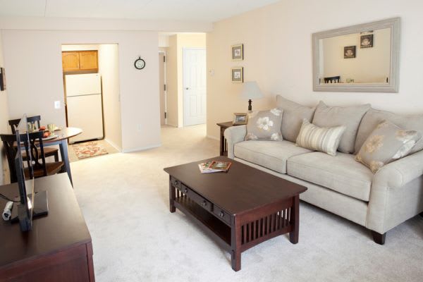 A cozy living room with a sofa and coffee table, featuring neutral tones and simple decor.